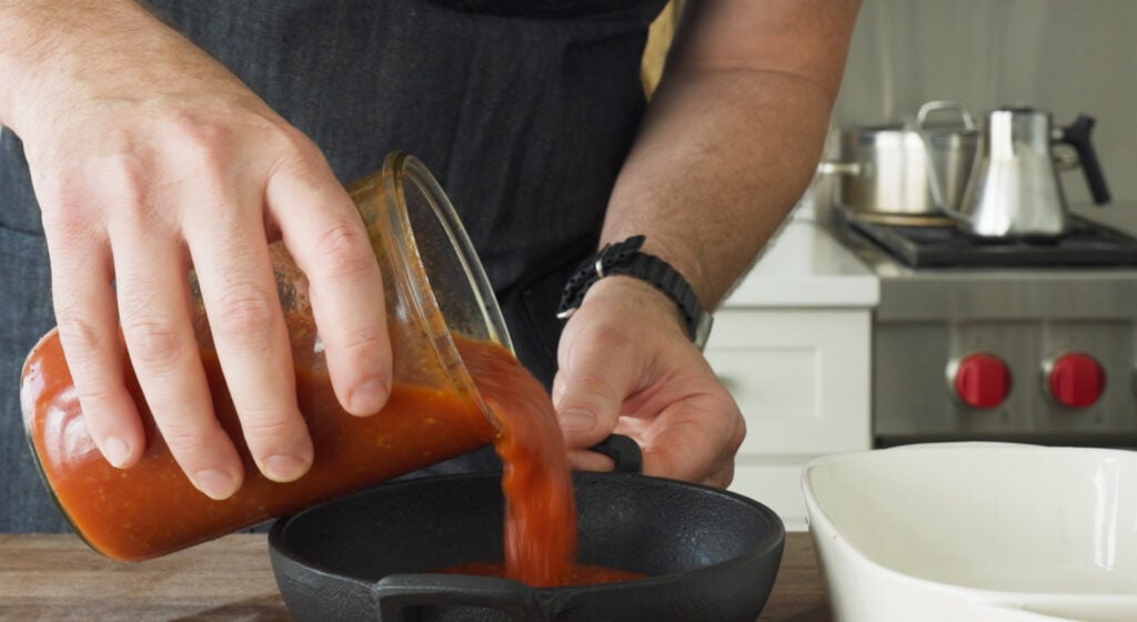 pouring pomodoro sauce into a dish