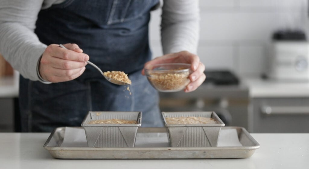 sprinkling walnuts and brown sugar onto raw banana bread