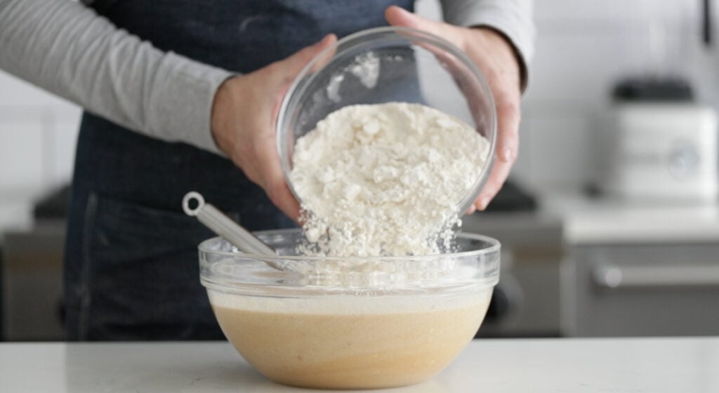 whisking flour in a bowl with melted butter and eggs