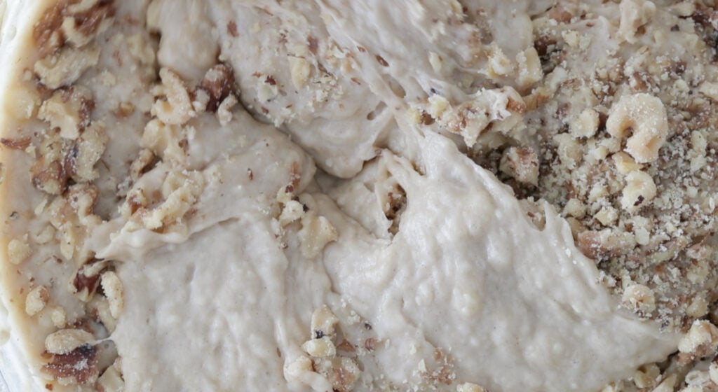 folding walnuts with flour into a bowl