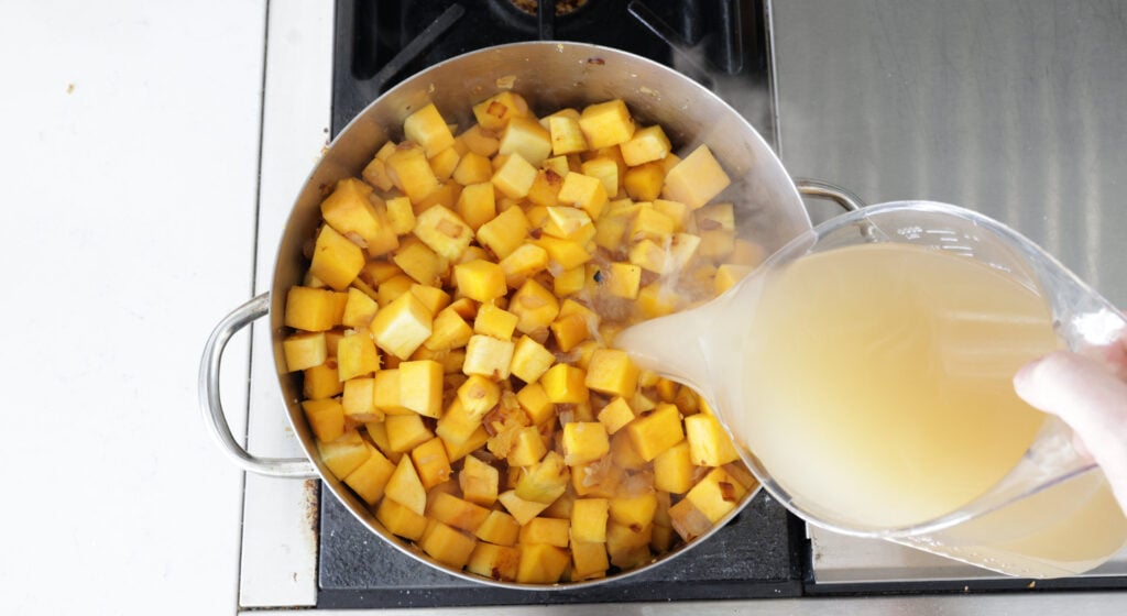 pouring broth to cubed butternut squash