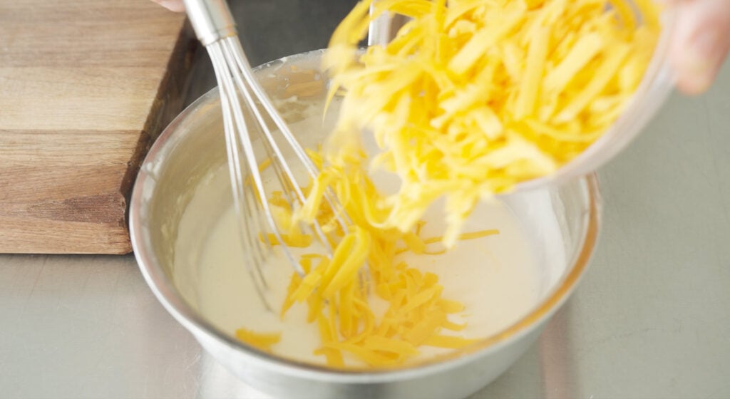 Cup with cheese being added to mixture