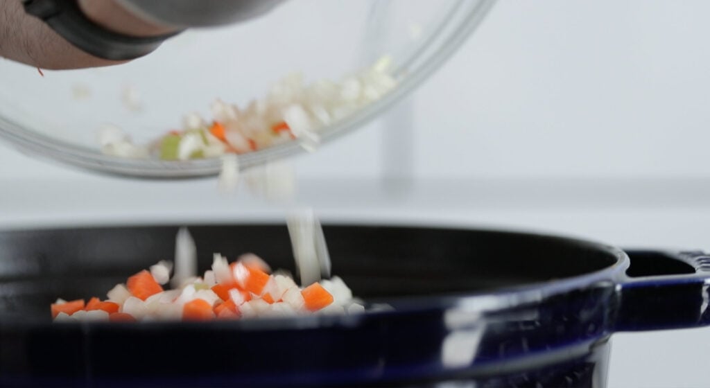 adding vegetables to the soup pot