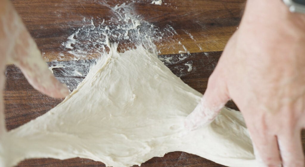 dough being stretched on clean surface