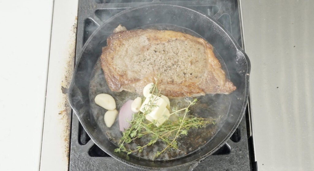 ribeye in pan with butter, garlic, shallot and thyme
