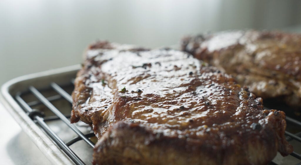 ribeye resting on a rack over a pan