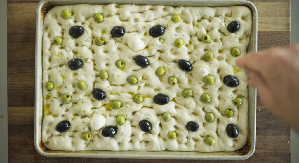 Uncooked focaccia with olives added on top