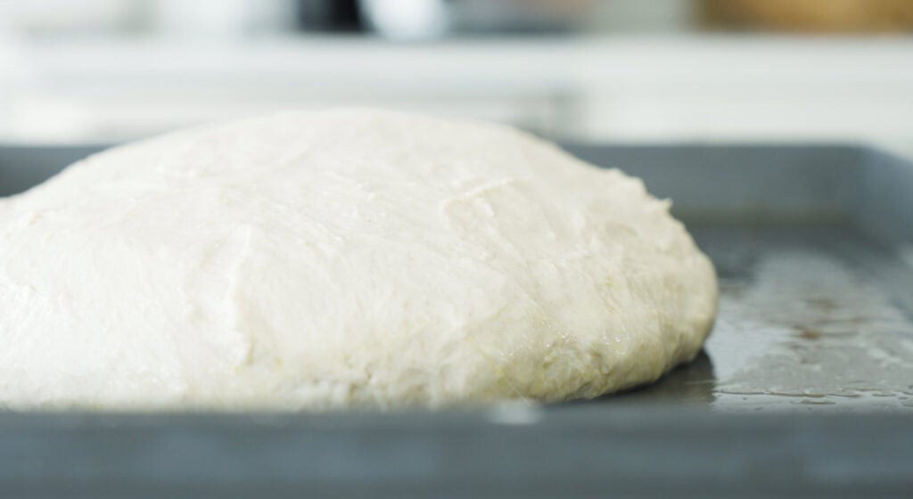 ball of dough resting on oiled pan