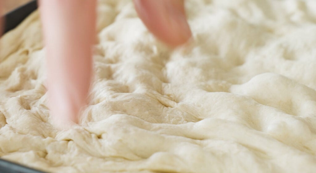 fingers creating dimples in dough