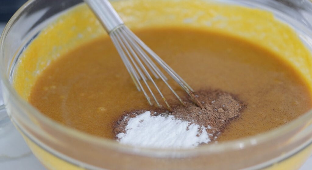 adding baking powder to a pumpkin bread batter