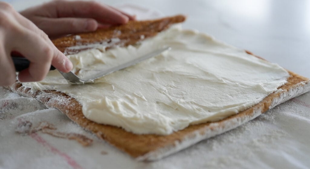 spreading cream cheese on a pumpkin cake