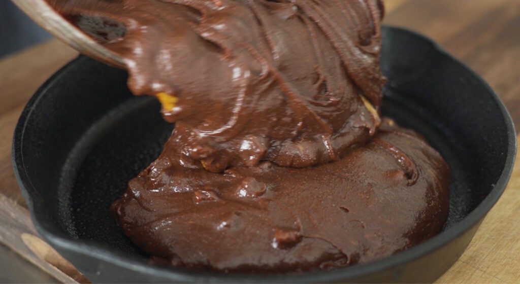 Pouring brownie batter into cast iron skillet