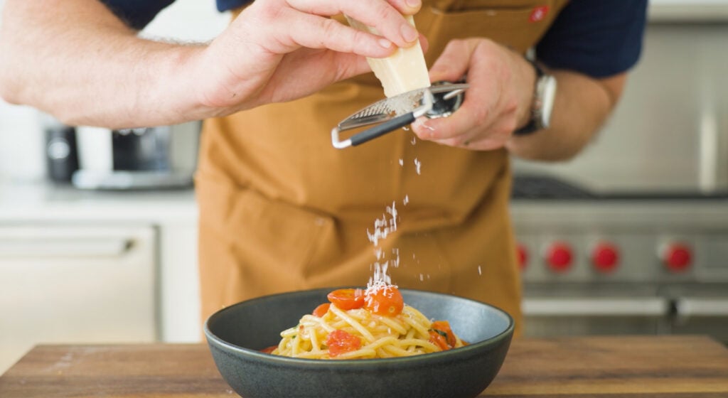 garnishing tomato basil pasta with cheese
