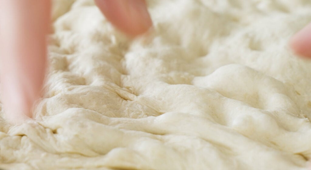 finger creating dimples in dough