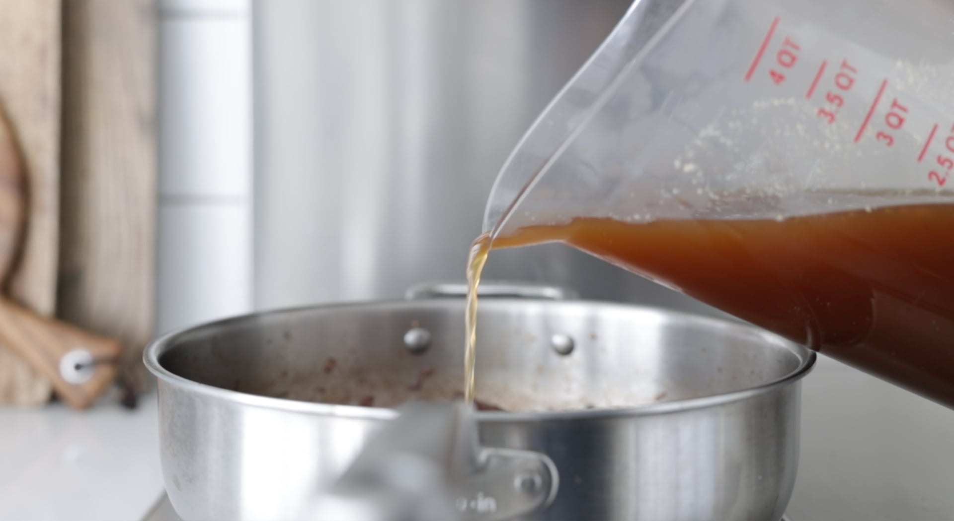 adding beef stock to a pot