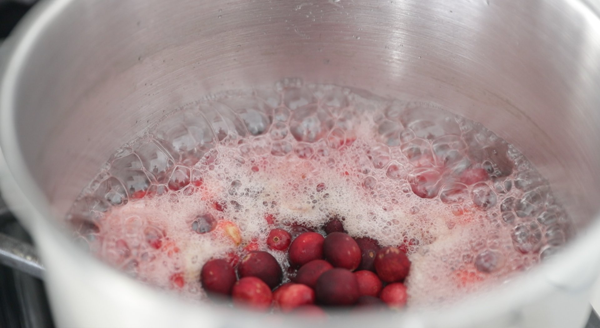 adding cranberries to sugar and water