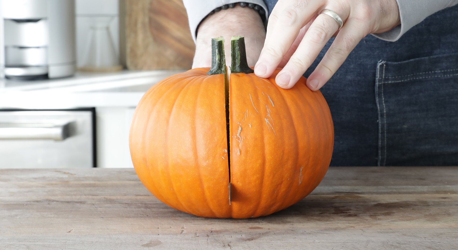 slicing the pumpkin in half with a long sharp knife