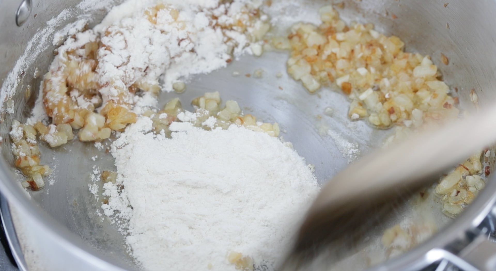 stirring flour into onions and garlic in a pot