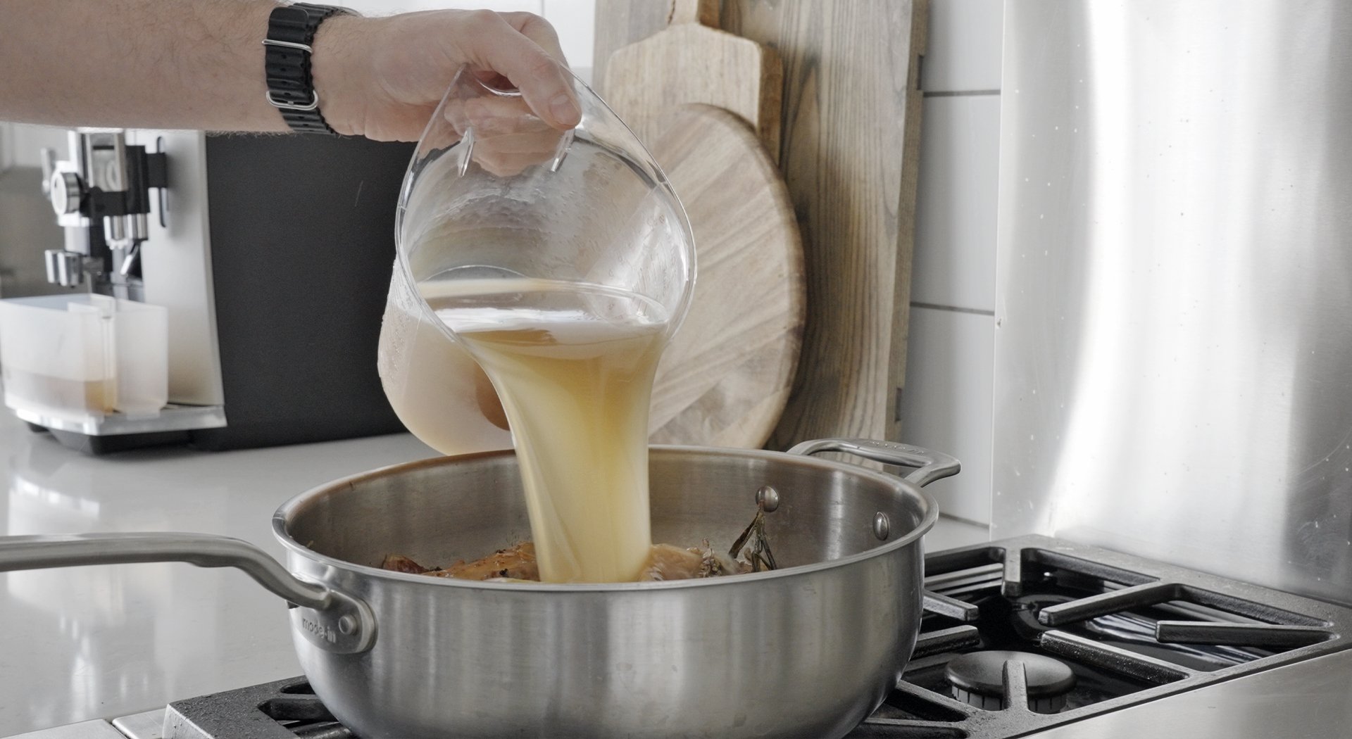 pouring chicken stock in a pot