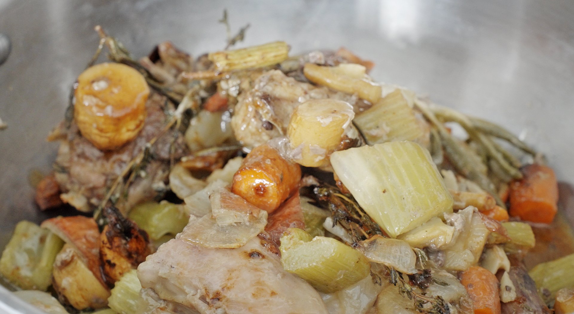 adding roasted veggies and turkey parts to a pot
