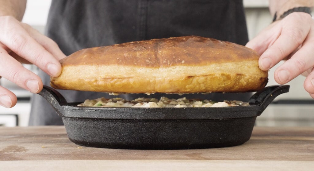 Placing baked puffed pastry on top of  filling in serving dish