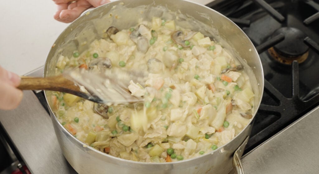Stirring finished Chicken Pot Pie filling in a pot