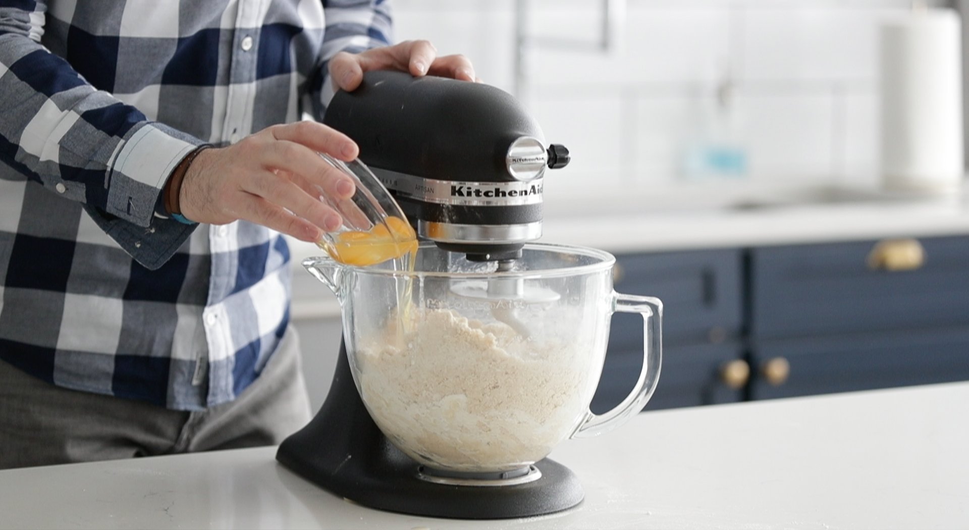 adding eggs to a stand mixer with dough