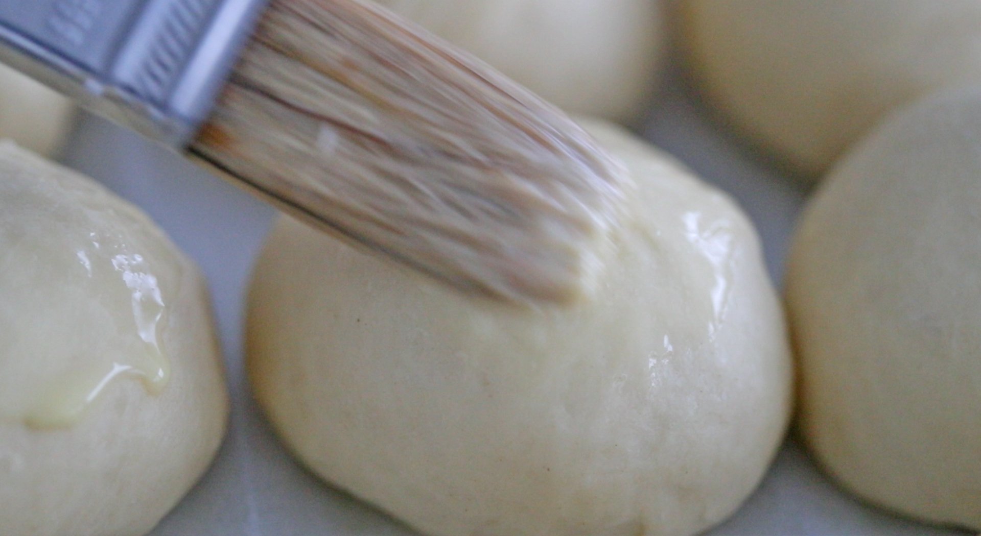 brushing a dough ball with a whisked egg