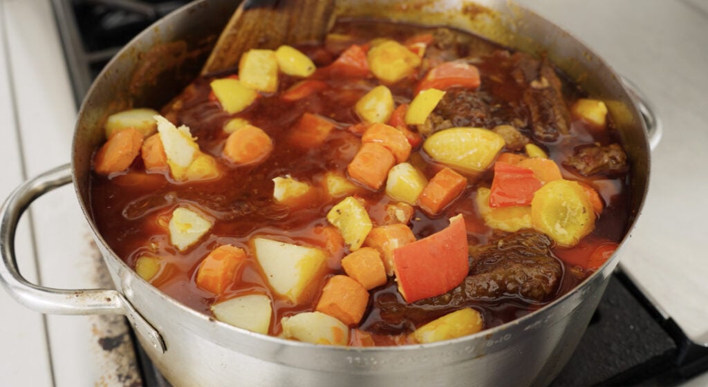 carrots, peppers, potatoes and beef in large stainless steel pot