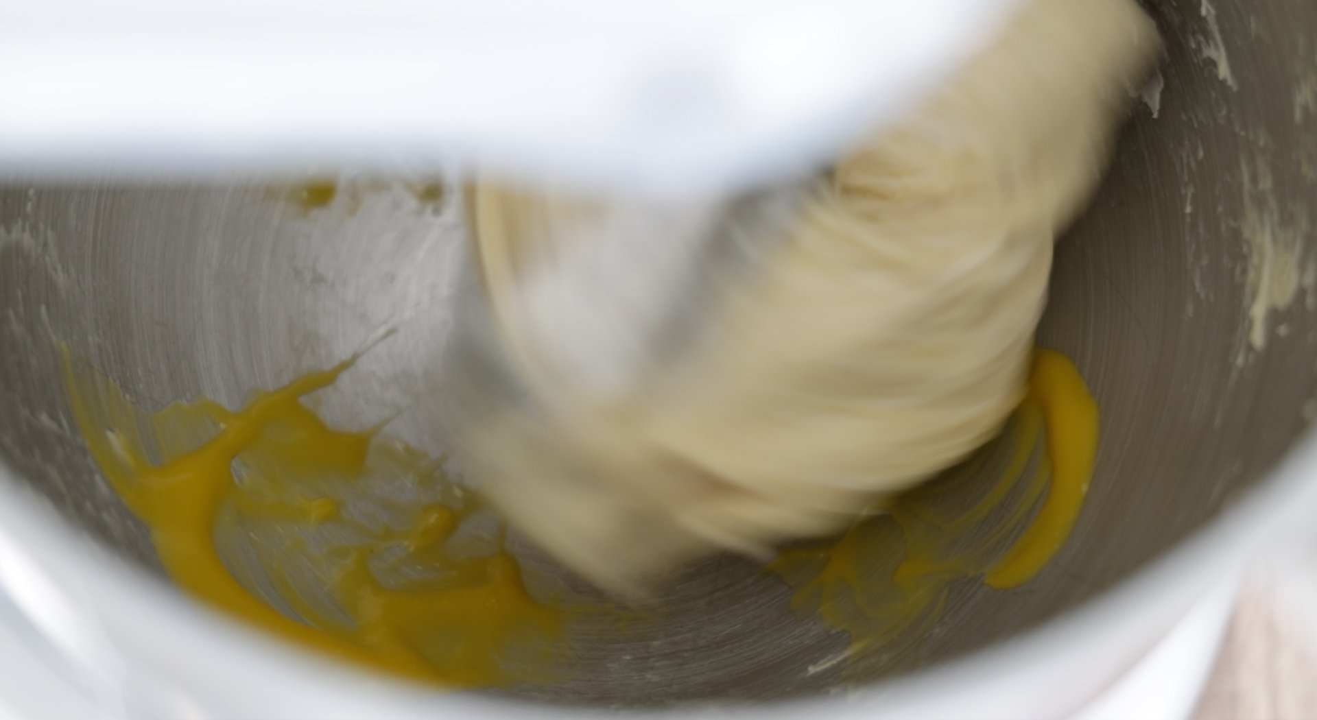 adding egg yolks to a bowl of dough