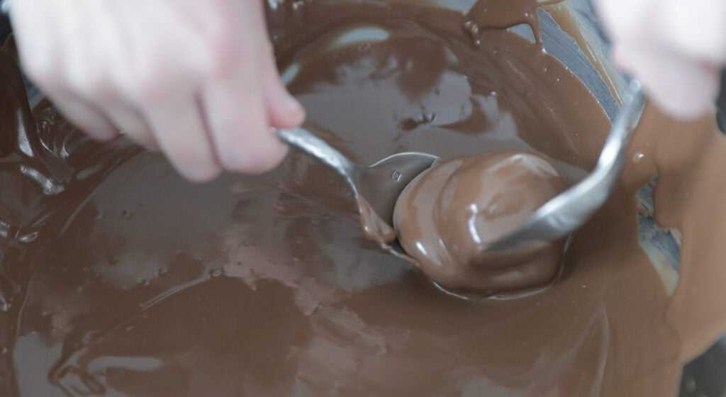 one peanut butter ball in the melted chocolate bowl