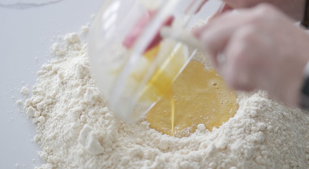adding whisked eggs to the center of a flour well
