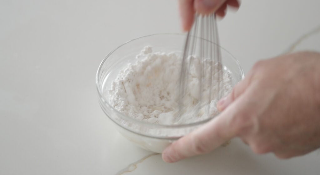 whisking together powdered sugar and milk in a bowl