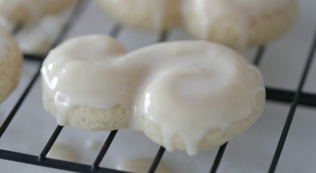 dipping baked s cookies into powdered sugar glaze
