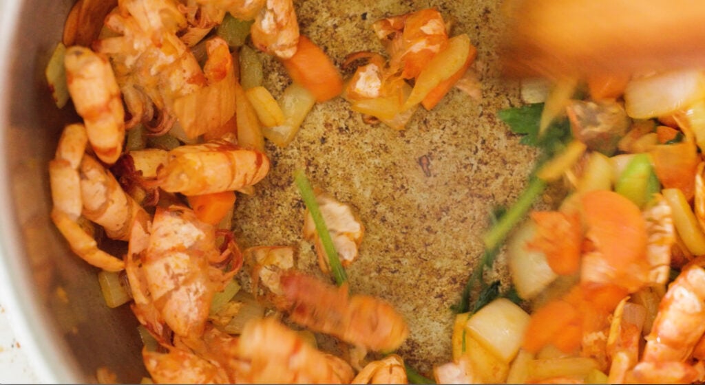 Browned bottom of the pot with shrimp shells and aromatics on the sides
