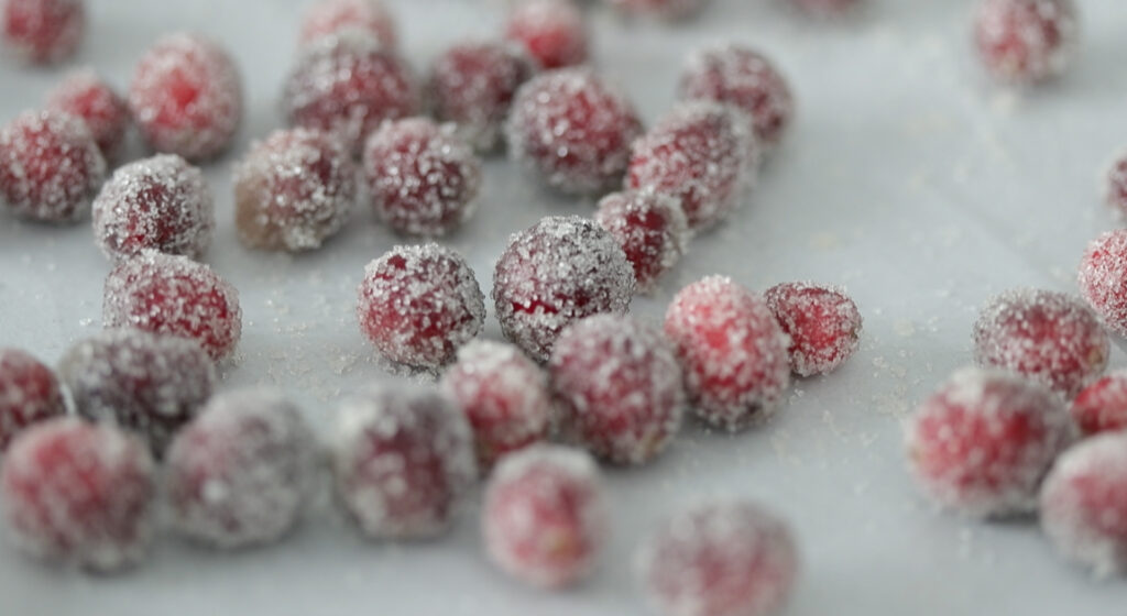 coated cranberries on a parchment cookie sheet