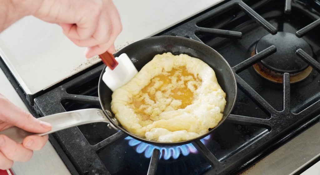 Omelette begining to puff up in pan over blue flame