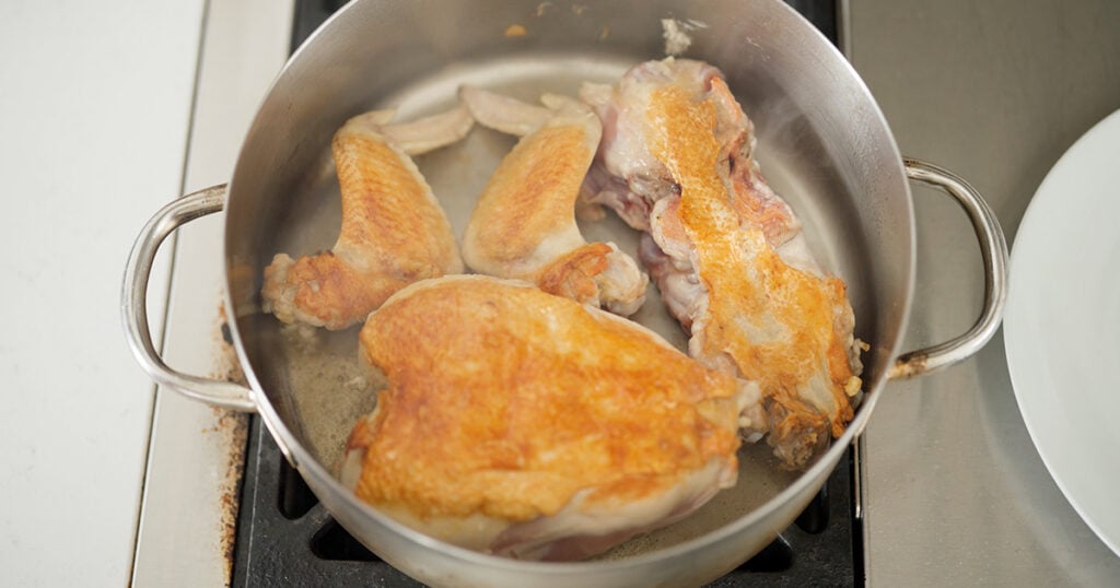 browned chicken pieces in a large pot