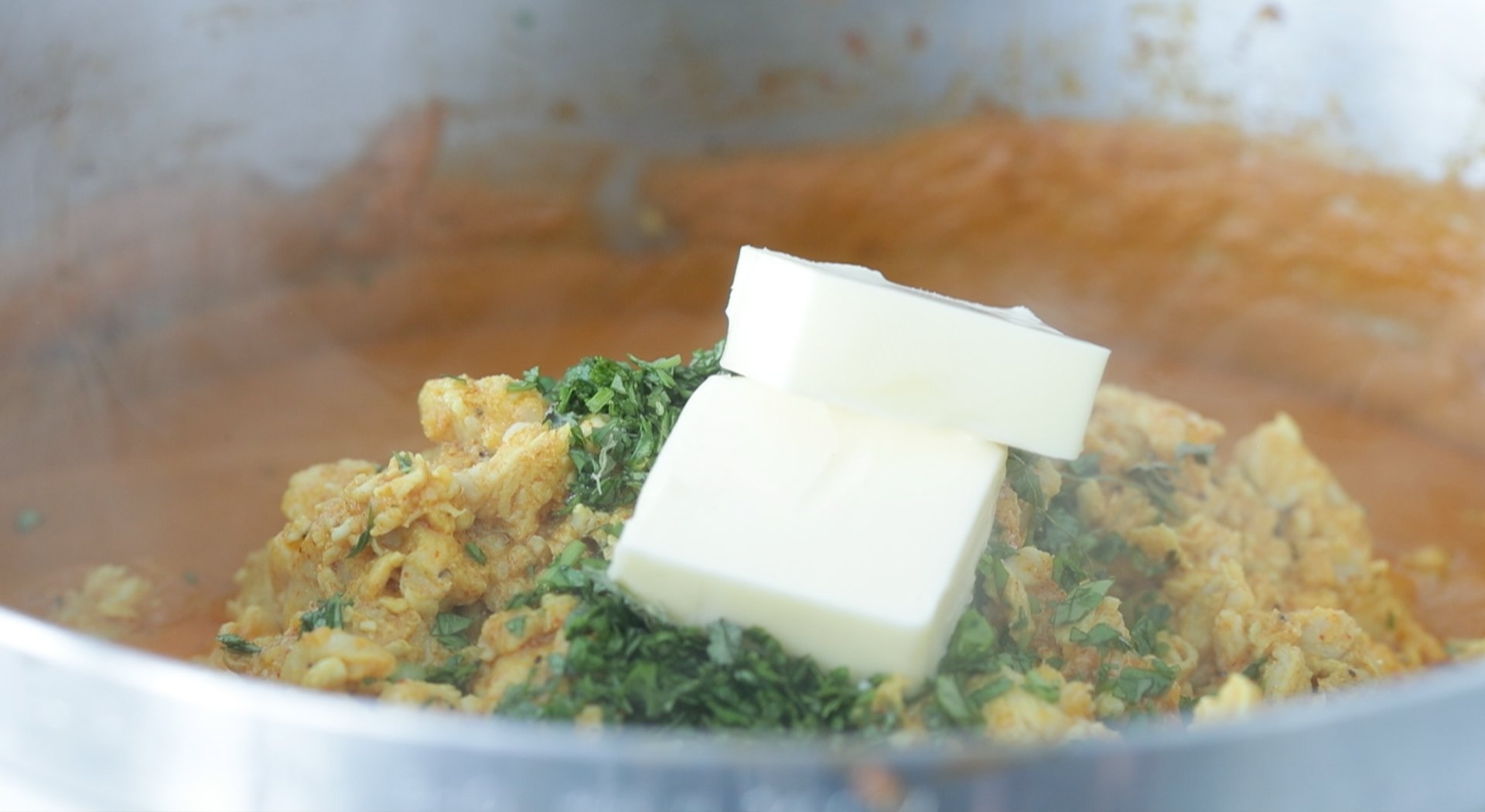 finishing butter chicken with butter and cilantro