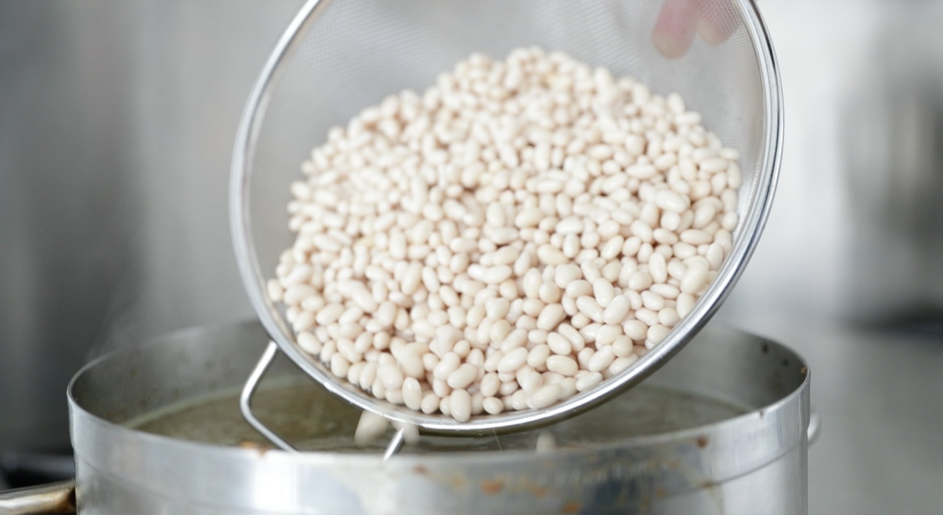adding soaked beans to a pot