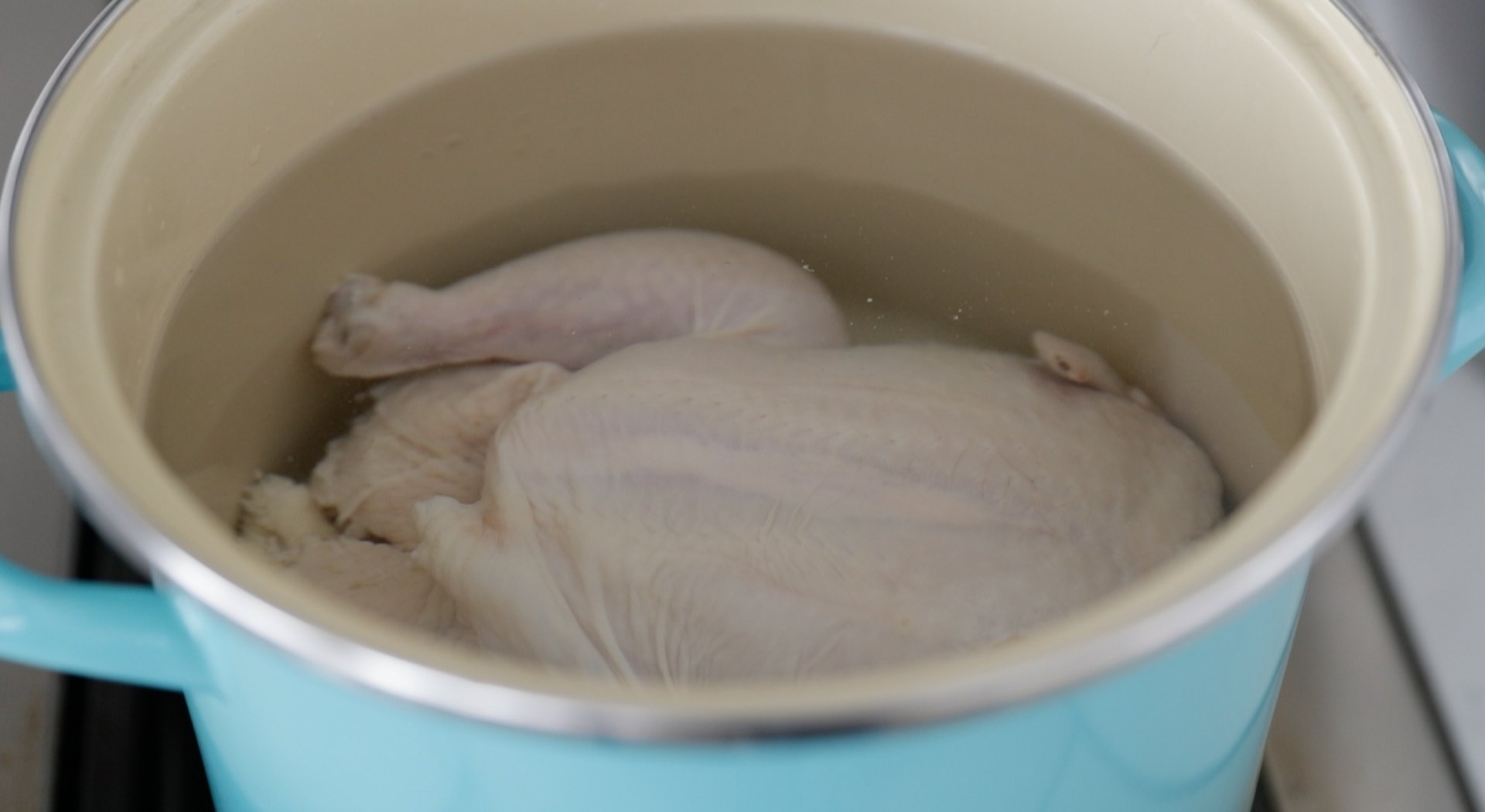 adding chicken to a pot of water