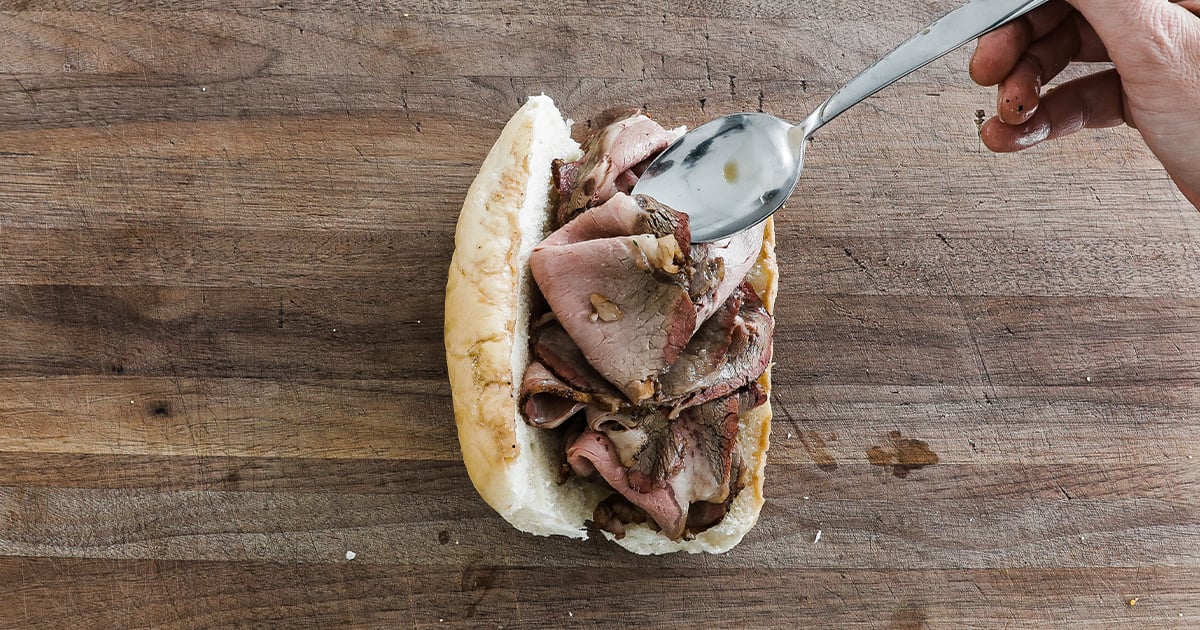 adding hot roast beef to a dipped bun