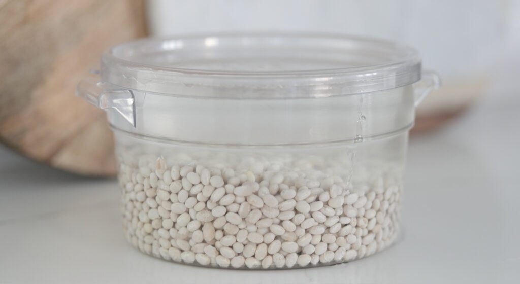 navy beans soaking in water in a container