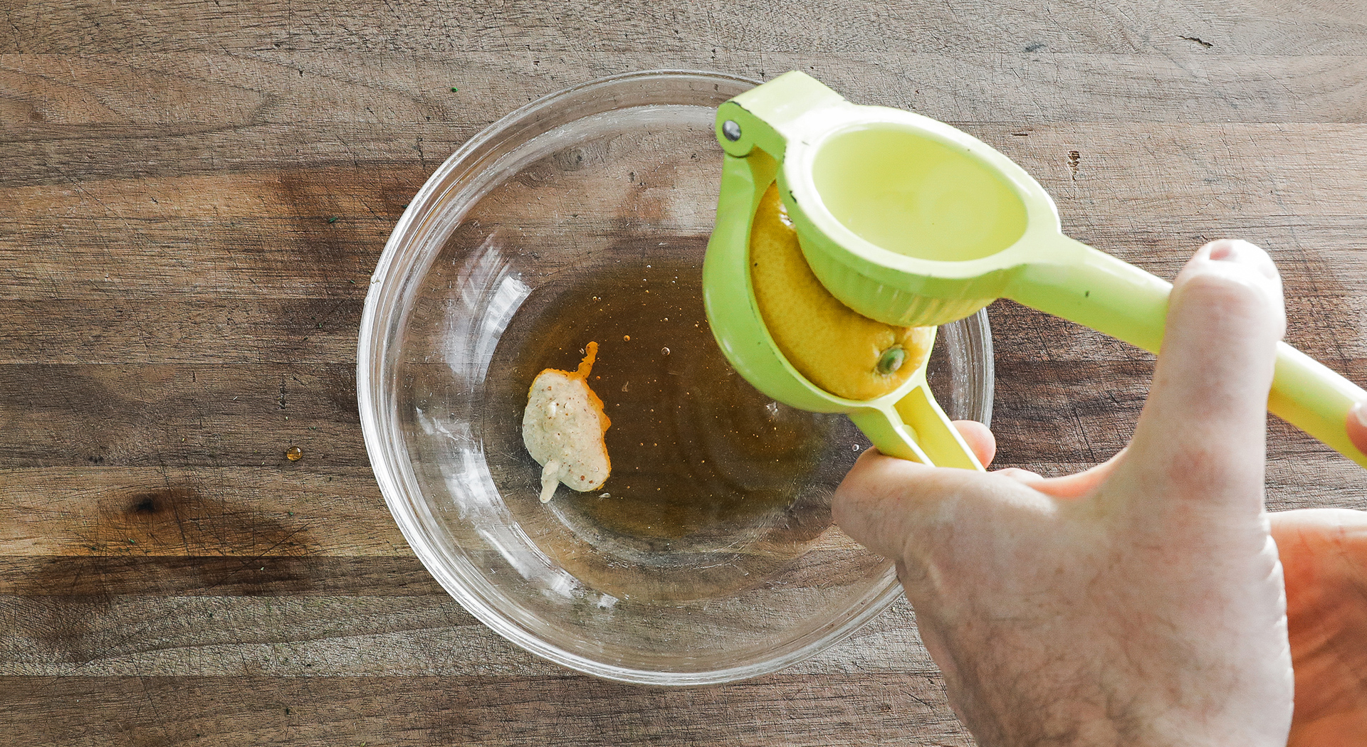 adding lemon juice to a bowl with vinegar and mustard