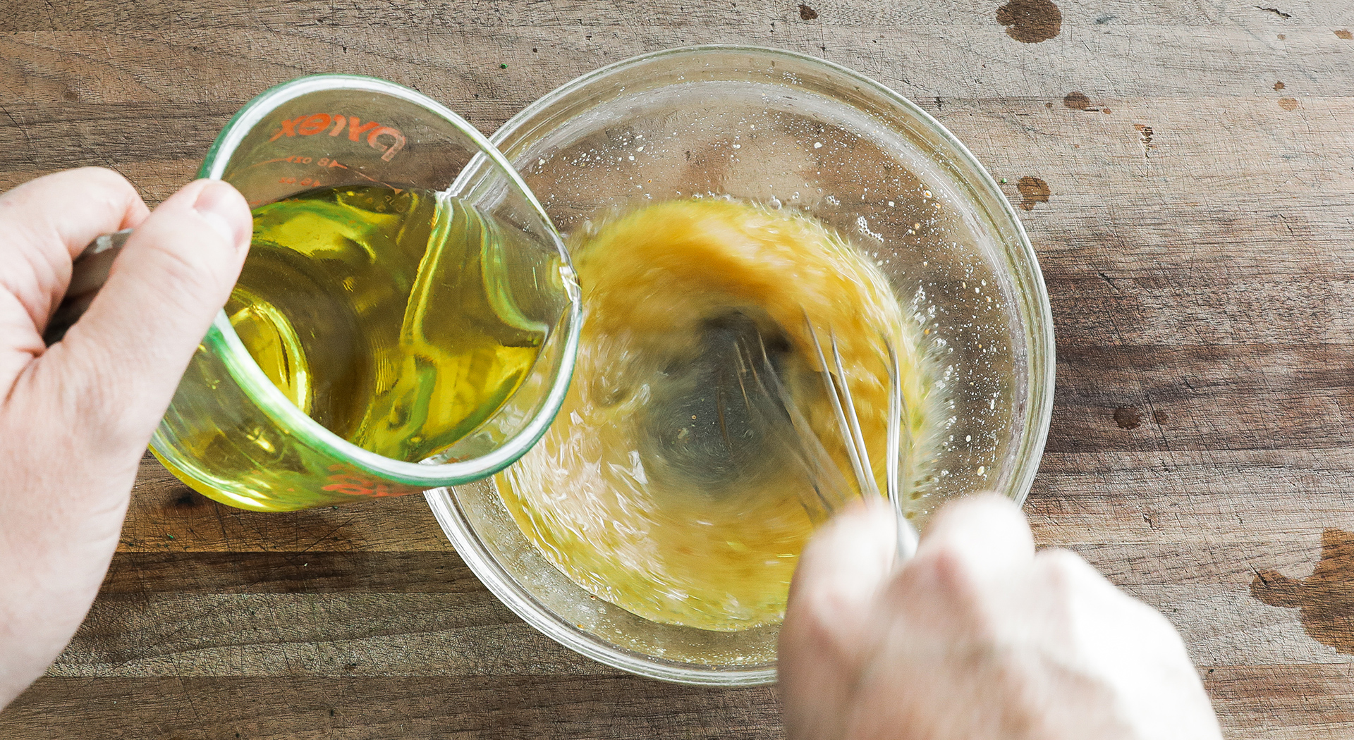 drizzling oil into a bowl while whisking