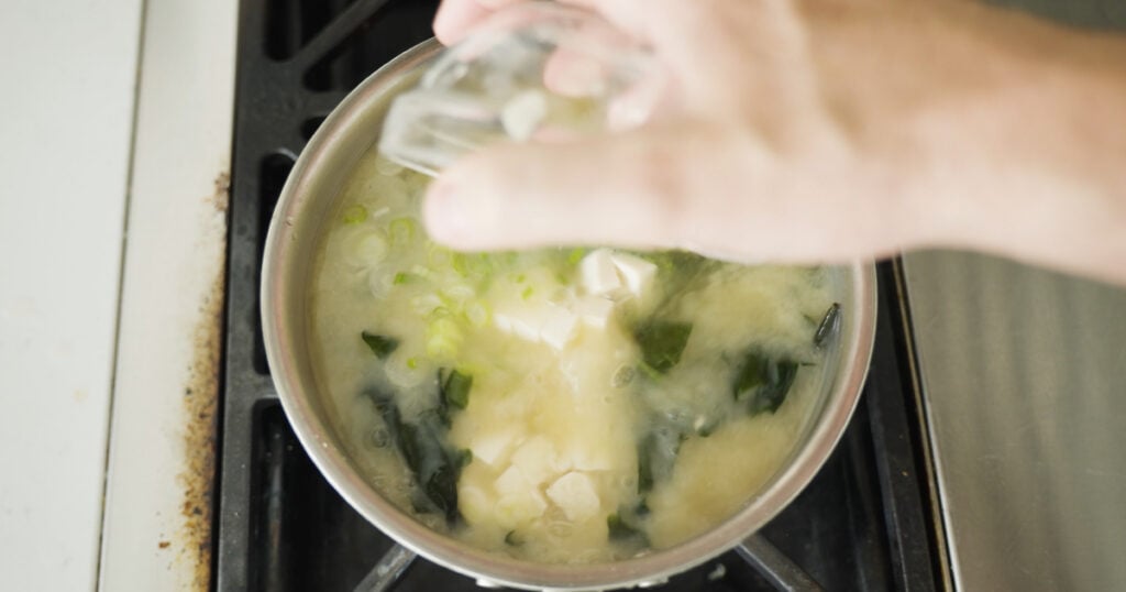 Tofu, green onions and wakame added to pot on the stove