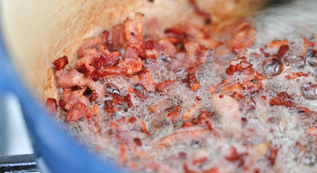 crispy bacon lardons cooking in a pot