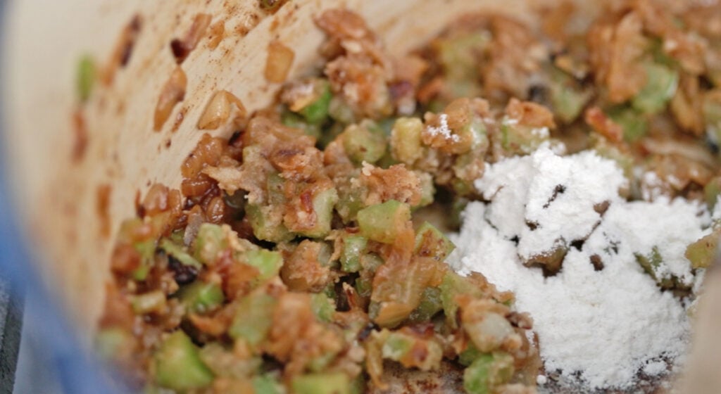 adding flour to cooked vegetables to make a roux