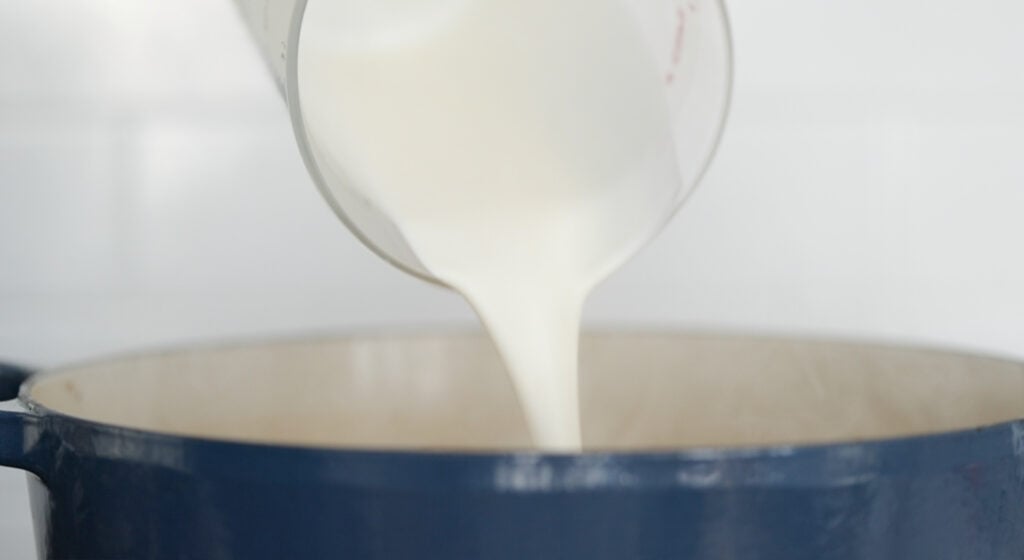 adding cream to a pot of potato soup