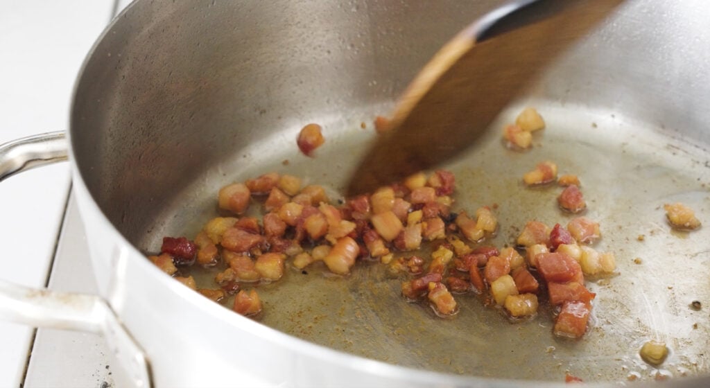 stirring pancetta in a rondeau pot